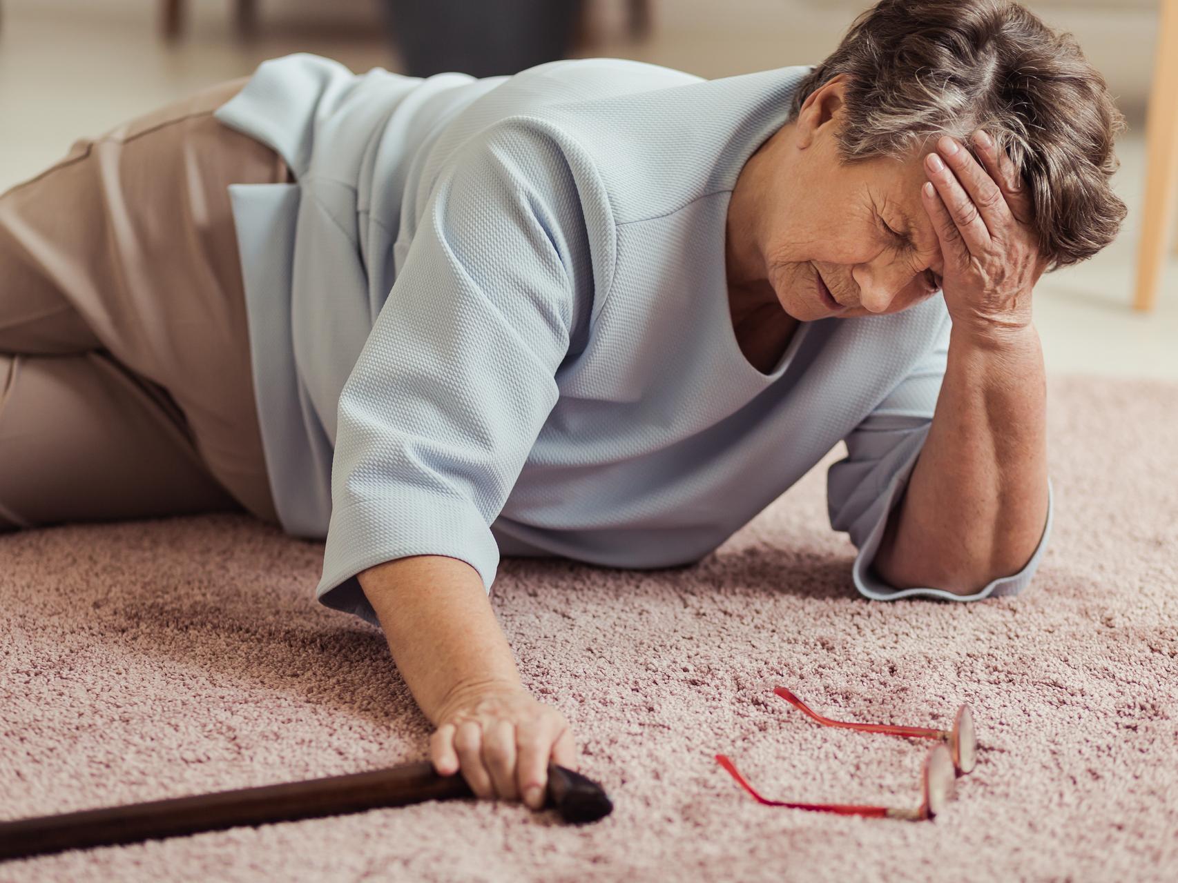 Ältere Frau, die auf dem Fußboden liegen, nachdem Sie gefallen ist | Foto: Photographee.eu 